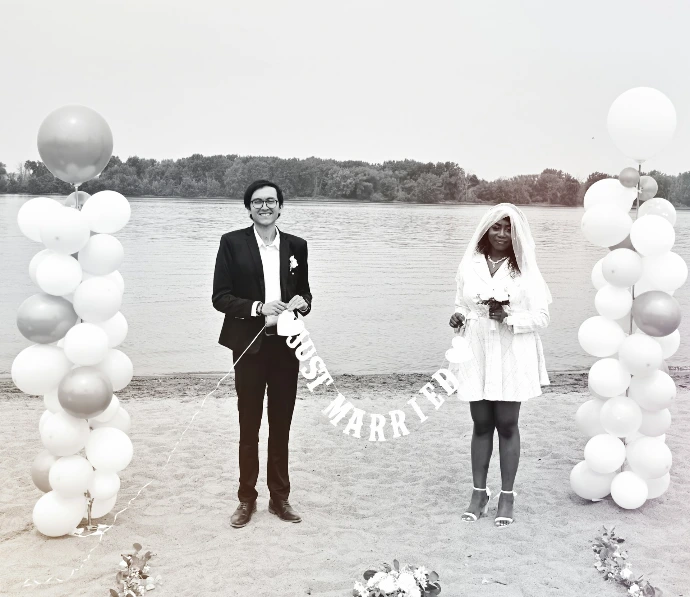 A man and a woman standing on a beach with balloons